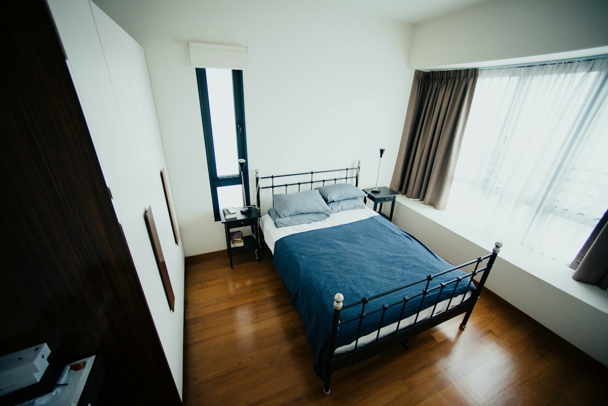 A simple bedroom with a metal bed frame and a large window