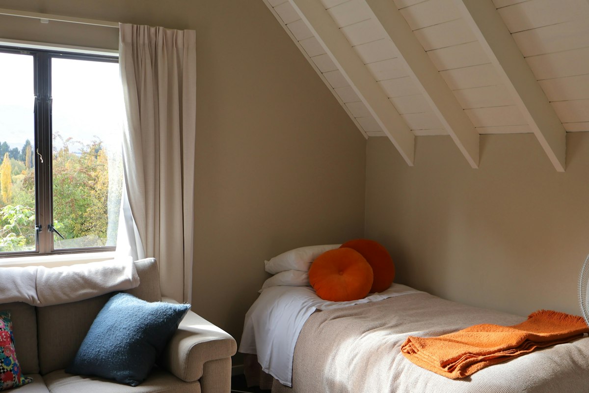 A small bedroom with a single bed by the window